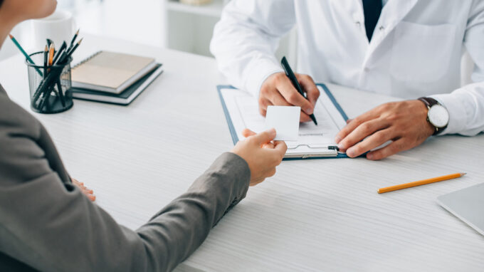 image of patient giving id card to doctor to fill medicare, medicaid, or other healthcare claim form in bluestem health clinic